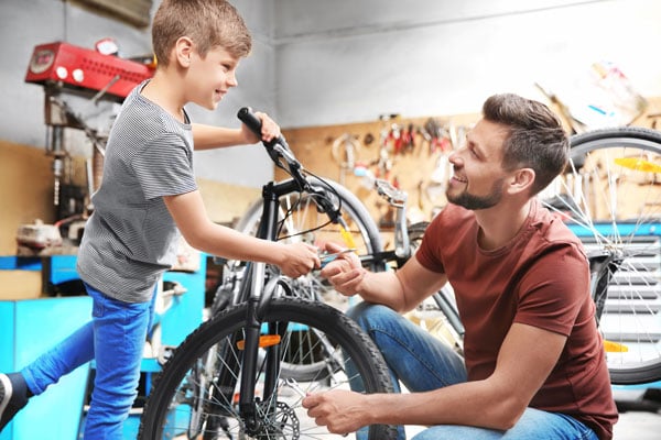Dad and kid working on bike in garage